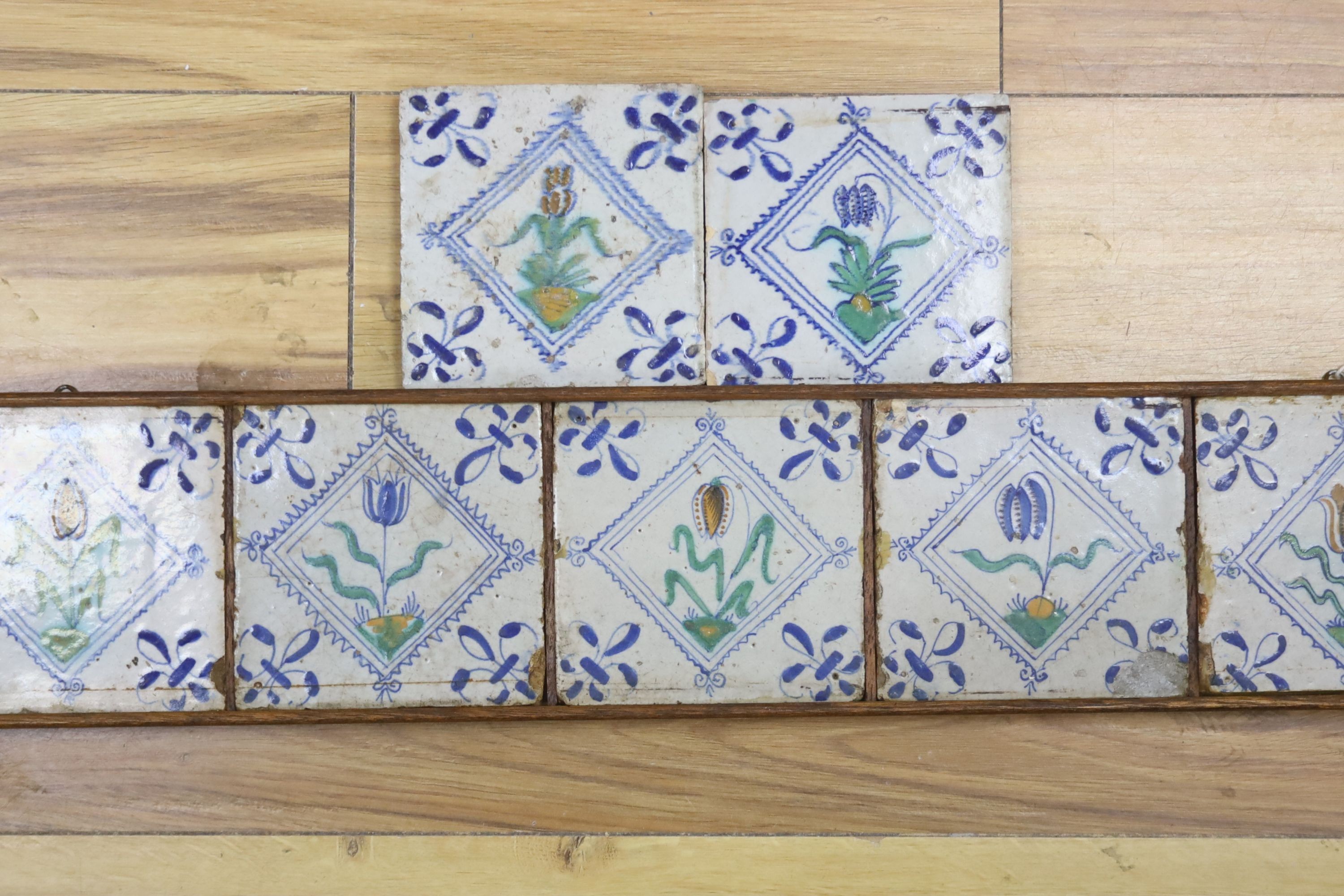 Seven 17th century Dutch Delft tiles, polychrome-decorated with tulips and having fleur-de-lys corners (framed 95cm)